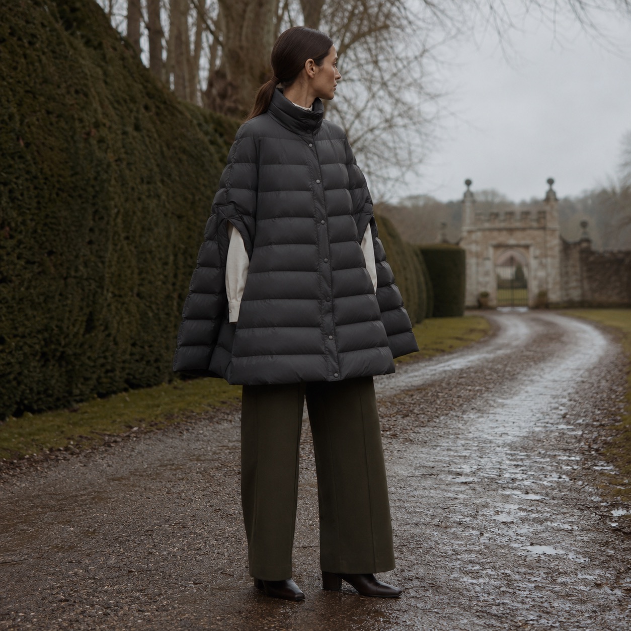 Cotswold wool cape with arm slits — Down & Cape Outerwear by MASO. worn by a model, side view.