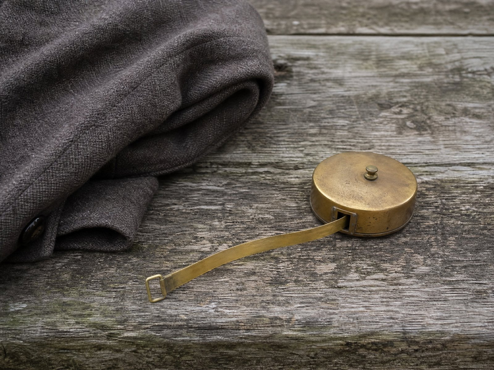 A folded ribbed knitted sock beside an uncoiled cloth tape measure